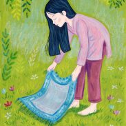 Fille dépliant un tapis dans l'herbe